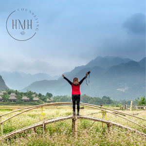 A person standing in nature with arms raised in triumph, facing majestic mountains. Symbolizing personal triumph, empowerment, and the journey to well-being.