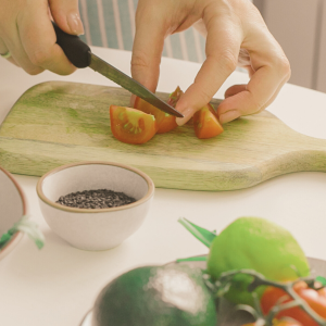 A photo of someone cutting a tomato to emphasize the importance of healthy eating for anxiety and stress management over the holidays. 